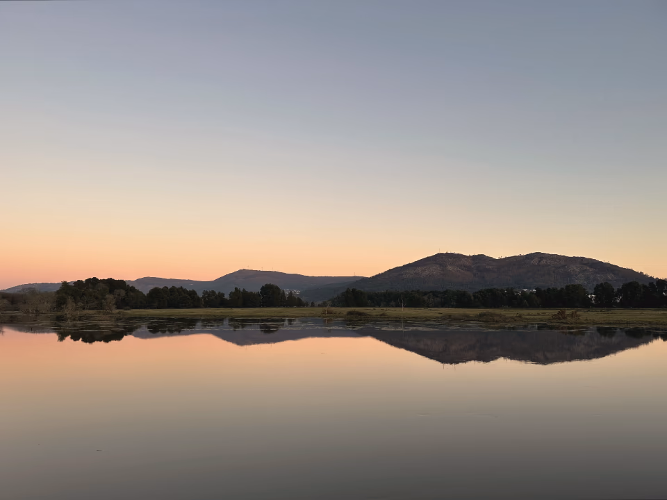 Lac au crépuscule, collines et ciel pastel reflétés dans l'eau immobile