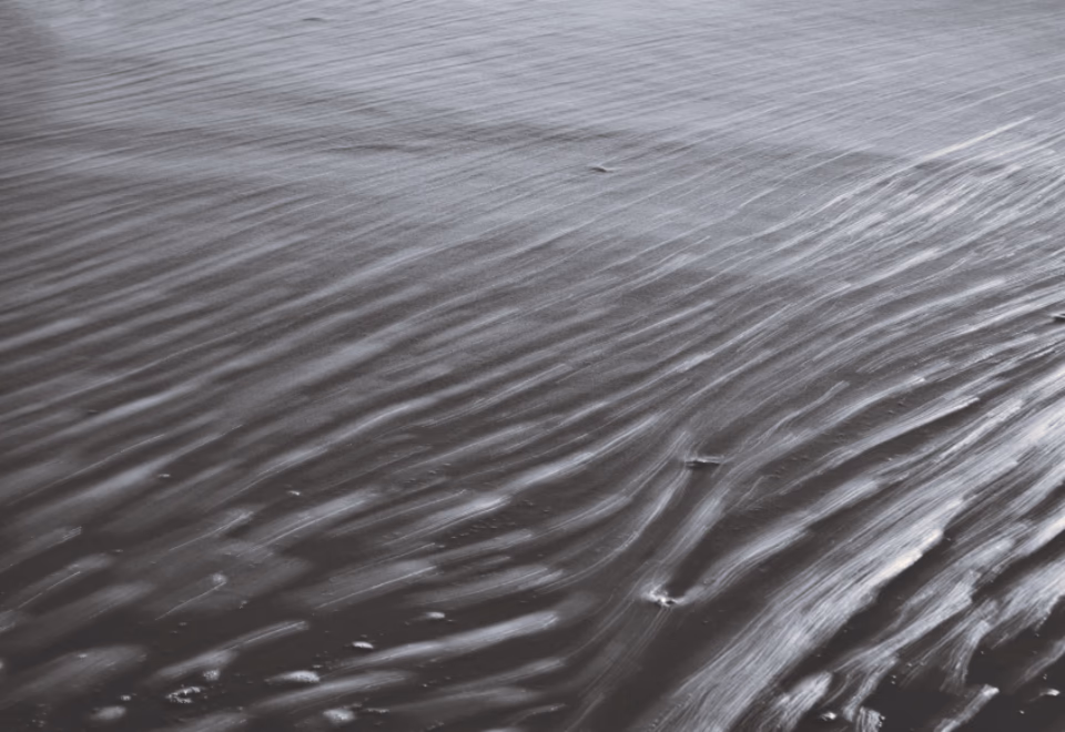 Surface d'une eau calme aux reflets argentés, parcourue de légères ondulations